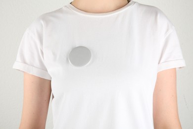 Photo of Woman with blank grey button badge on light background, closeup