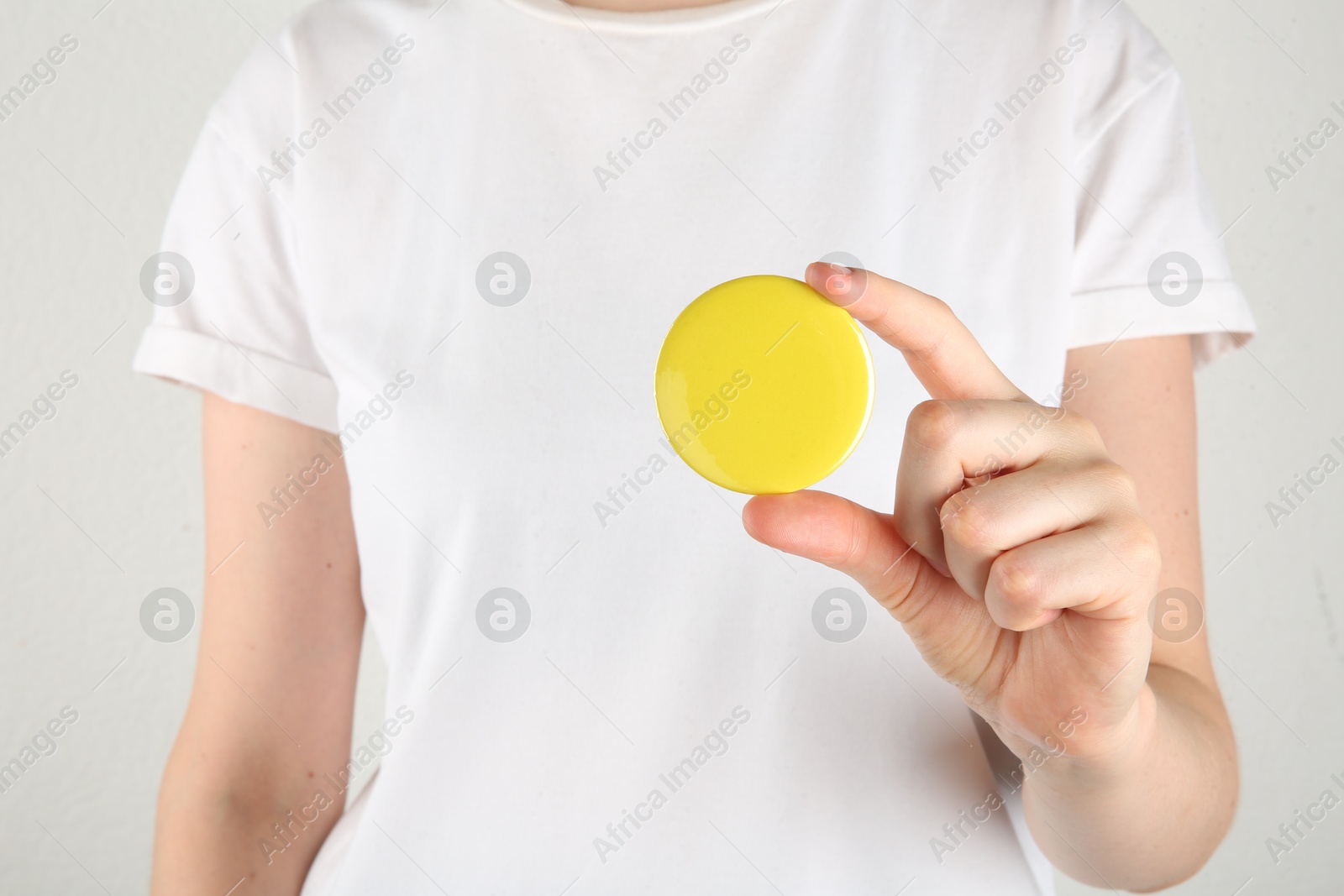 Photo of Woman with blank yellow button badge on light background, closeup