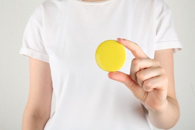 Photo of Woman with blank yellow button badge on light background, closeup