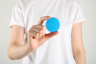 Woman with blank blue button badge on light background, closeup