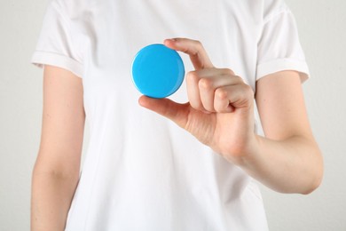 Woman with blank blue button badge on light background, closeup