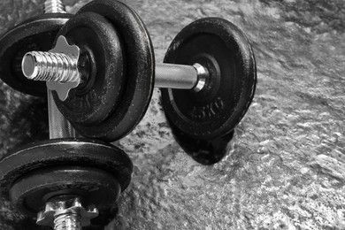 Photo of Barbells on dark textured floor, closeup. Space for text