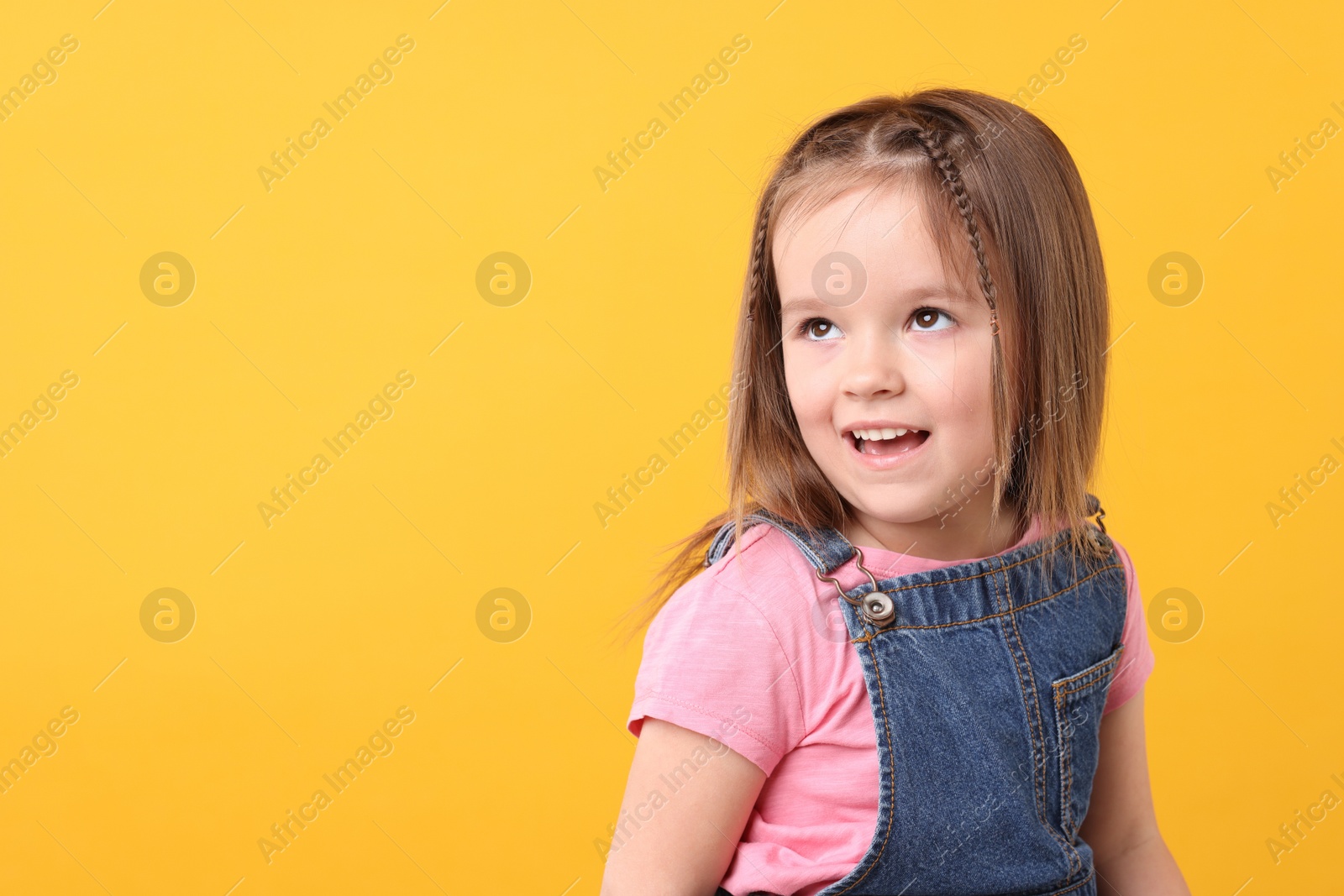 Photo of Portrait of cute little girl on orange background, space for text