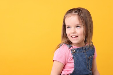 Photo of Portrait of cute little girl on orange background, space for text