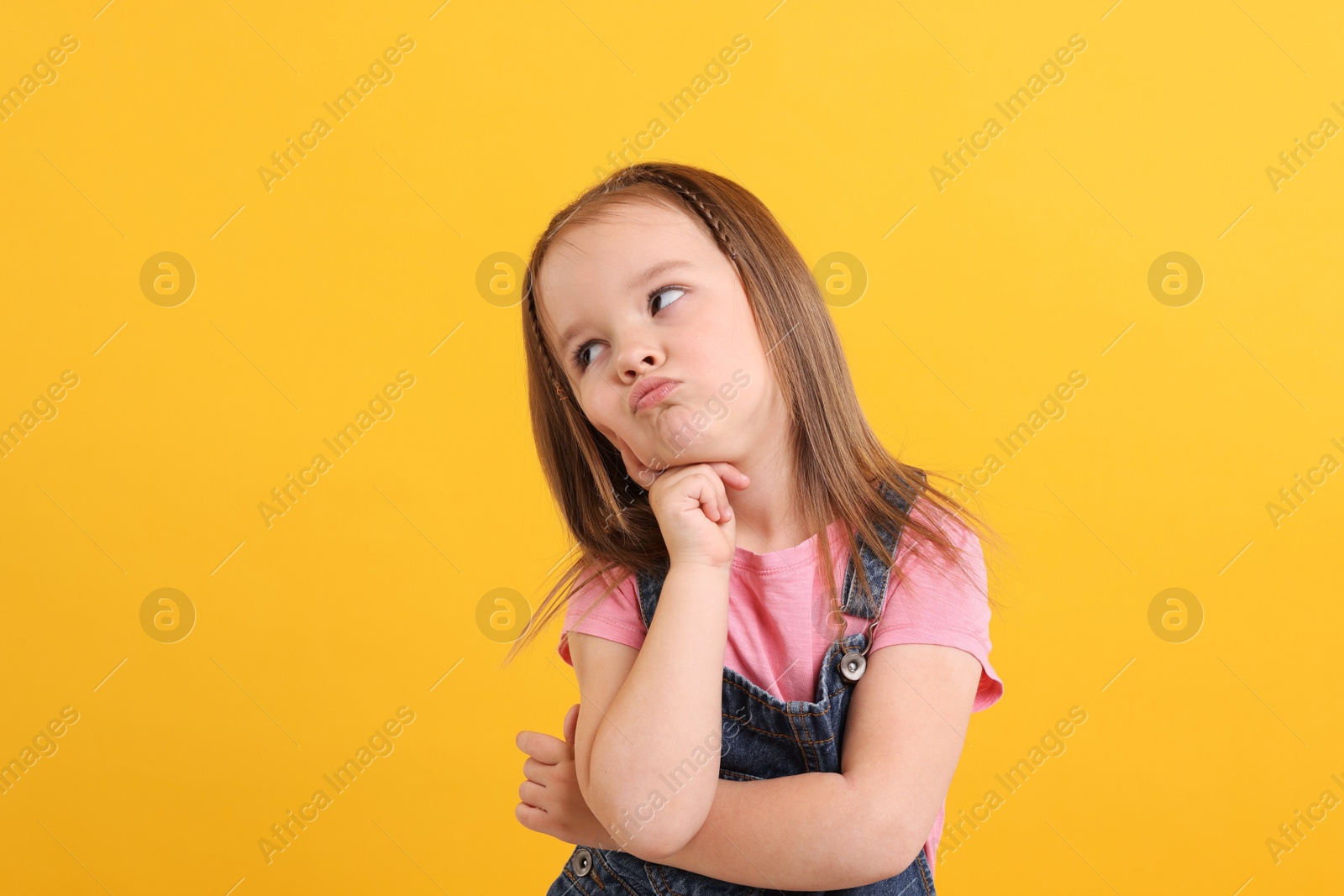 Photo of Portrait of cute little girl on orange background