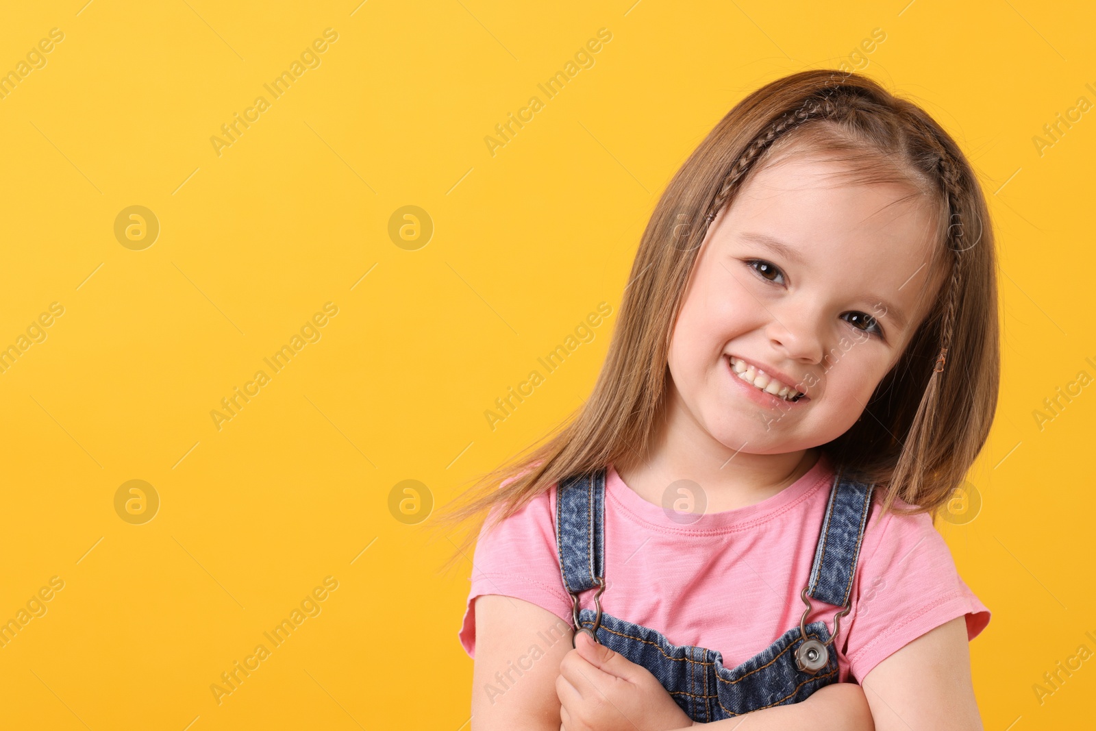 Photo of Portrait of happy little girl on orange background, space for text