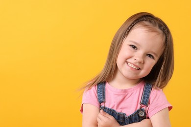 Portrait of happy little girl on orange background, space for text