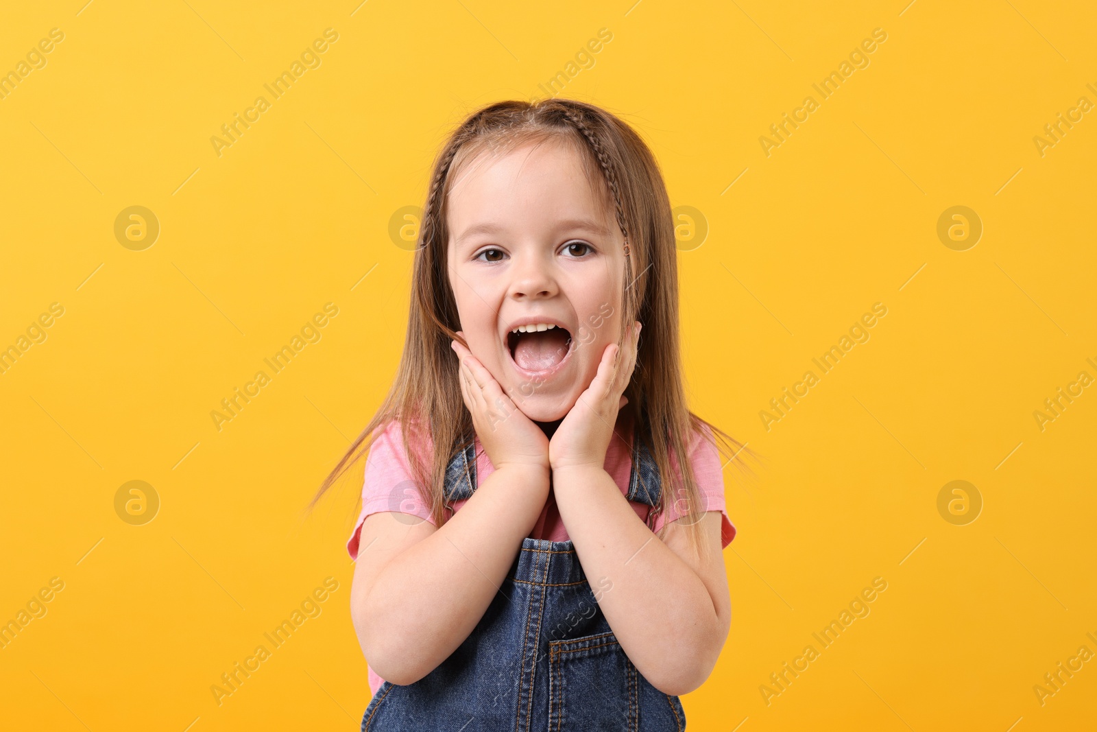 Photo of Portrait of emotional little girl on orange background