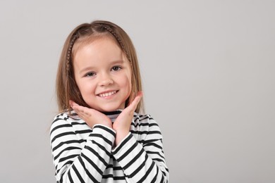 Photo of Portrait of happy little girl on grey background, space for text