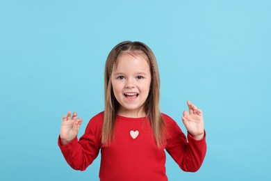 Portrait of happy little girl on light blue background