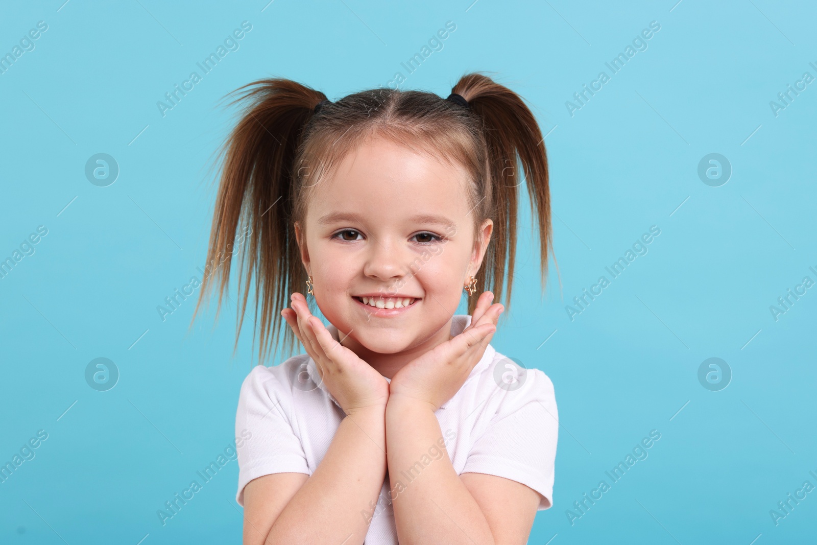 Photo of Portrait of happy little girl on light blue background