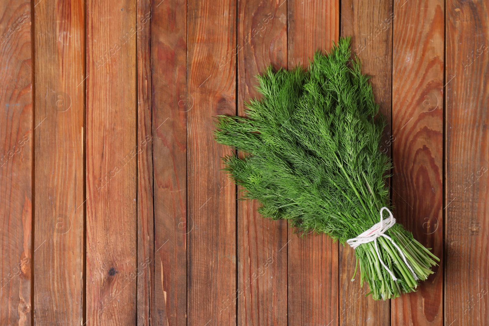 Photo of Bunch of fresh green dill on wooden table, top view. Space for text