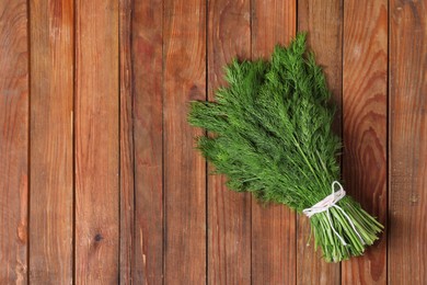 Photo of Bunch of fresh green dill on wooden table, top view. Space for text