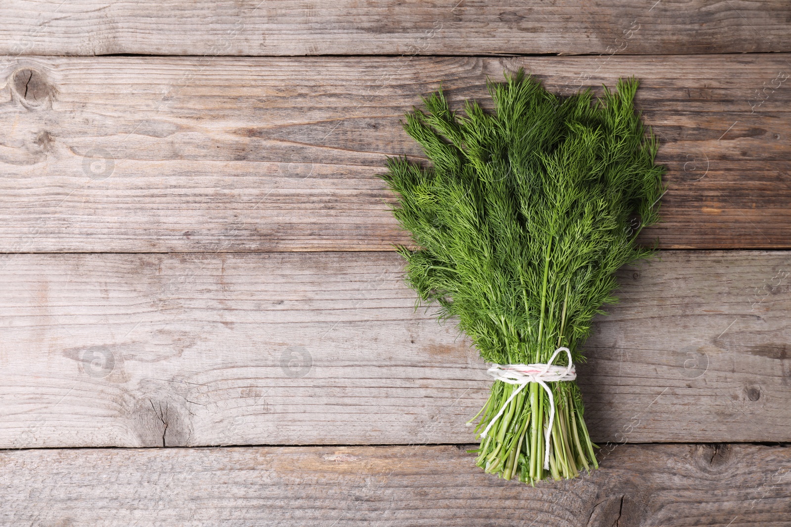 Photo of Bunch of fresh green dill on wooden table, top view. Space for text