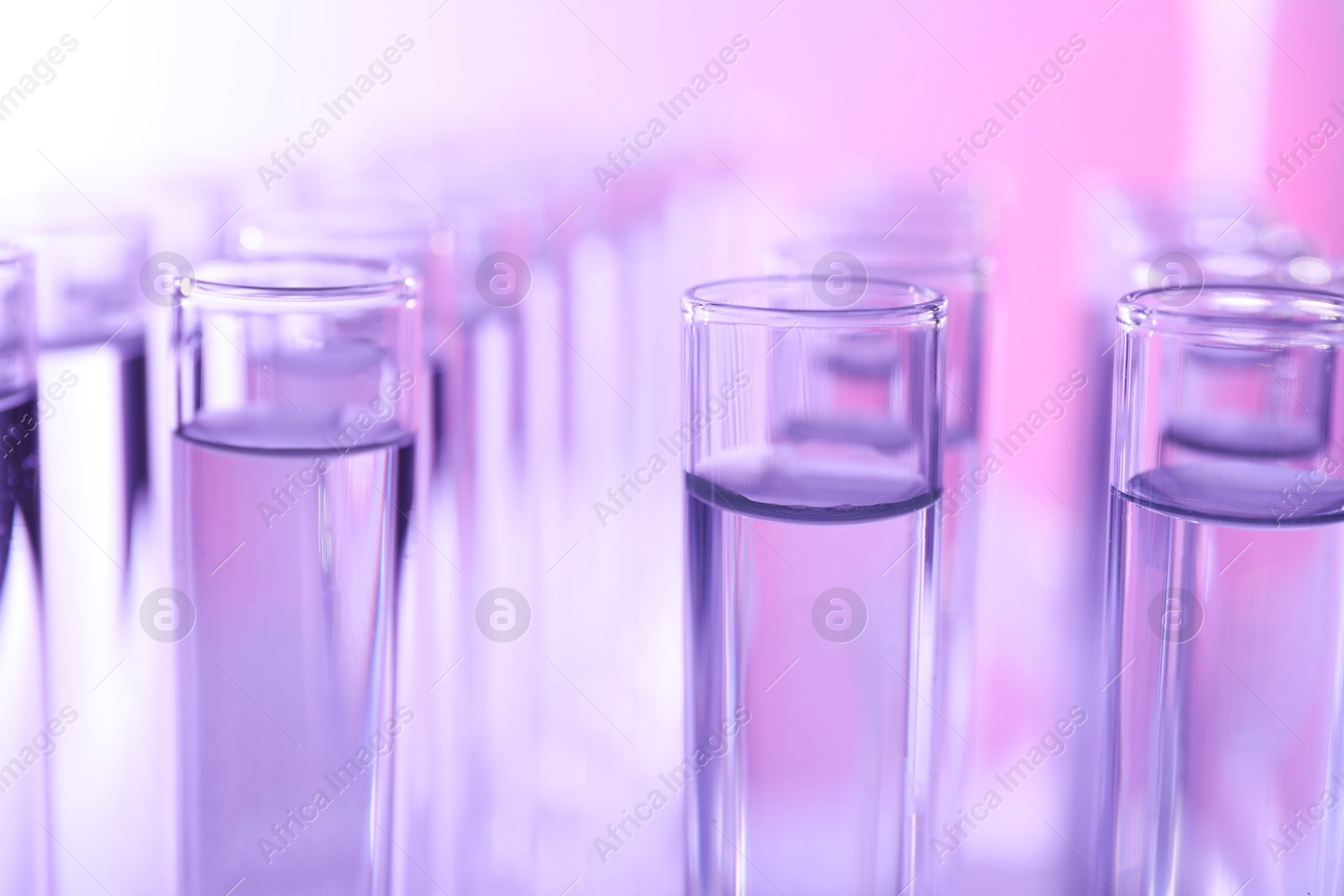 Photo of Many glass test tubes on color background, closeup