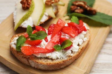 Delicious bruschettas with fresh ricotta (cream cheese), strawberry and mint on table, closeup