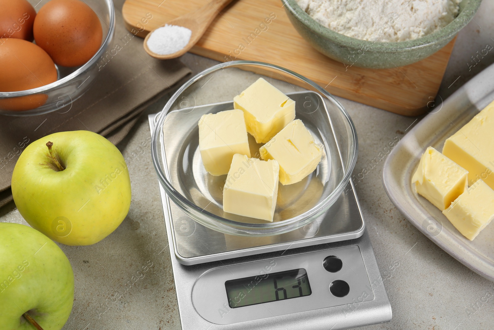 Photo of Kitchen scale with bowl of butter and other products on grey table