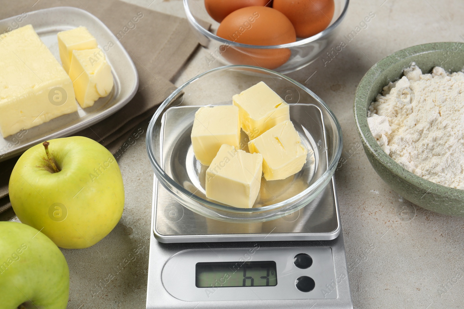 Photo of Kitchen scale with bowl of butter and other products on grey table