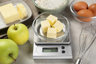 Photo of Kitchen scale with bowl of butter and other products on grey table