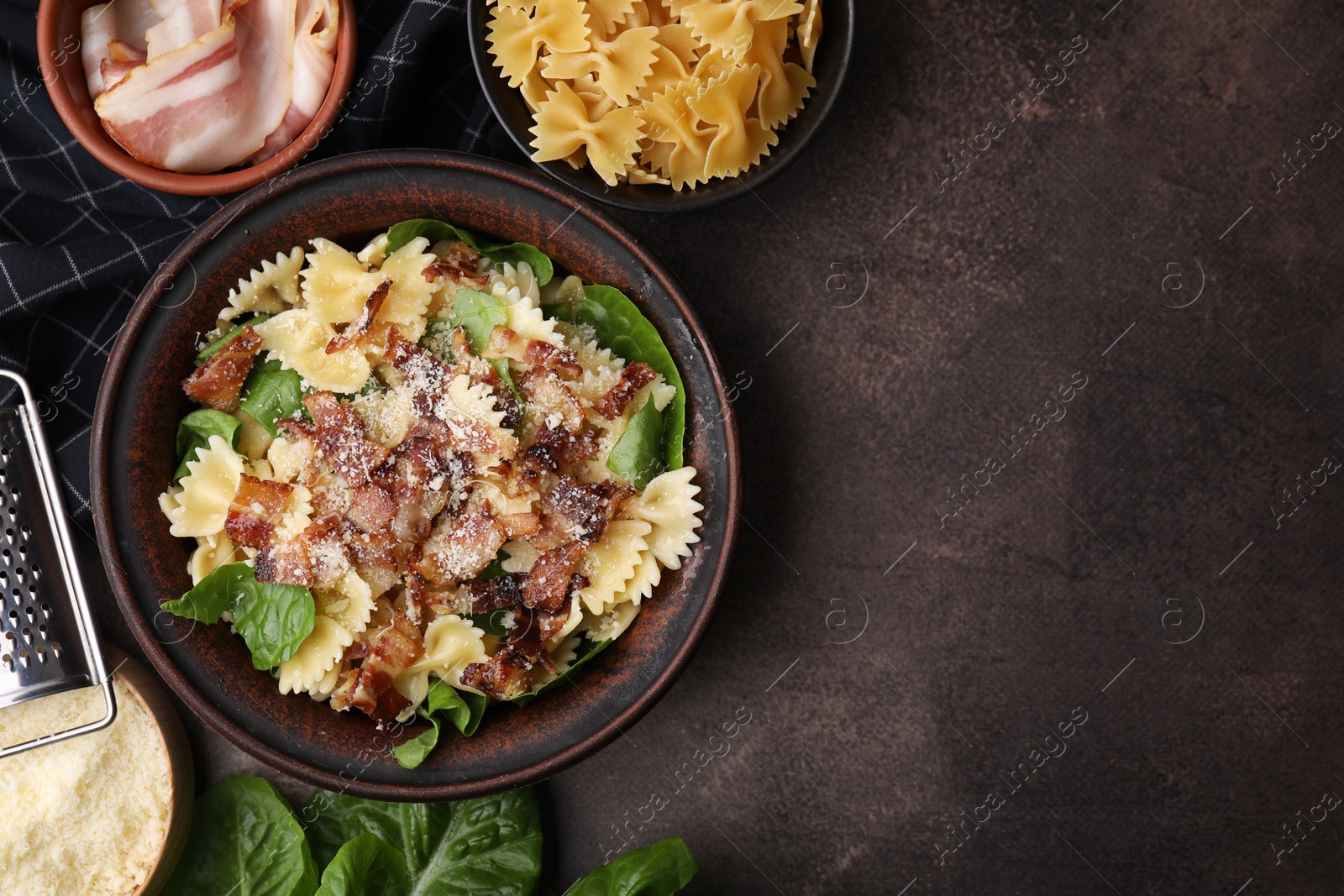 Photo of Tasty pasta with bacon and basil on brown table, flat lay. Space for text