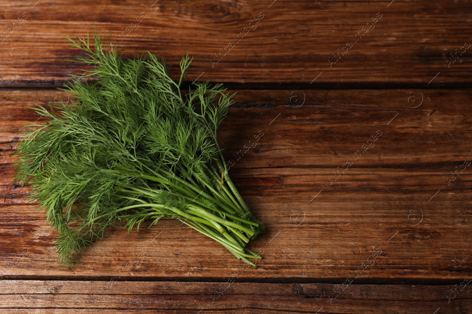 Photo of Sprigs of fresh green dill on wooden table, top view. Space for text