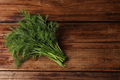 Photo of Sprigs of fresh green dill on wooden table, top view. Space for text