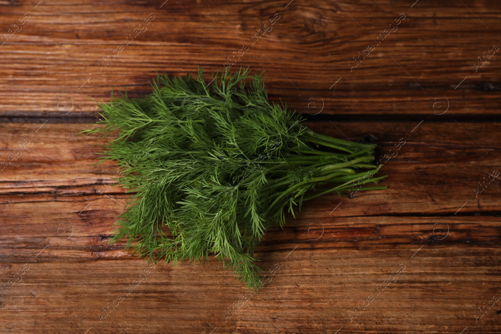 Photo of Sprigs of fresh green dill on wooden table, top view