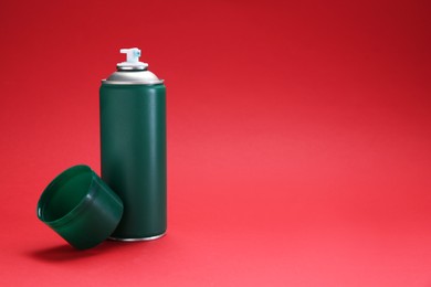 One green spray paint can on red background. Space for text