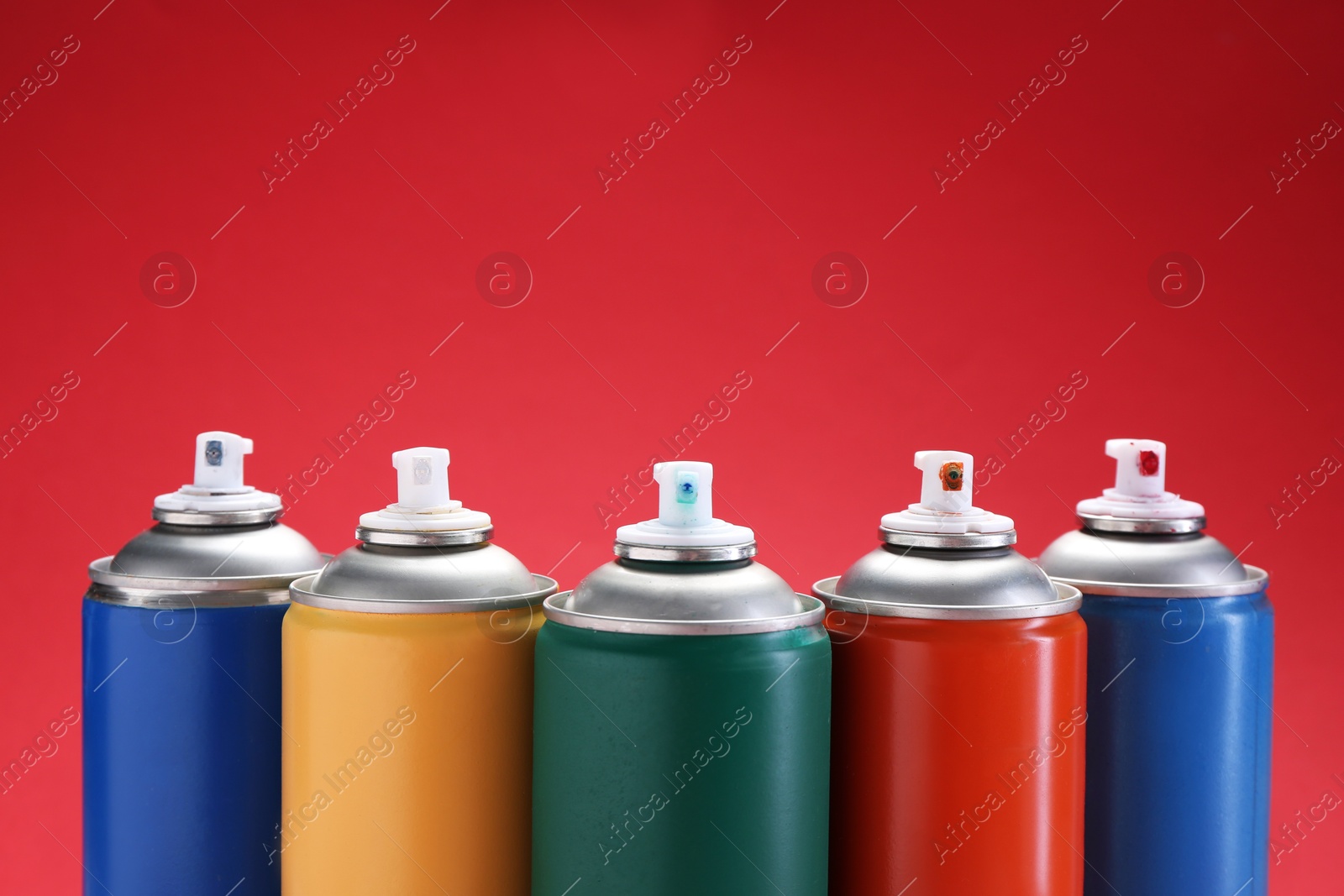 Photo of Many spray paint cans on red background. Space for text