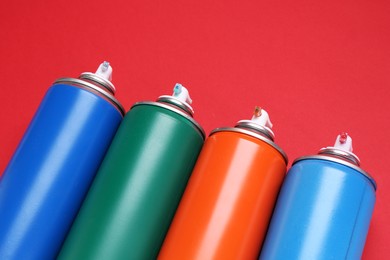 Many spray paint cans on red background, closeup