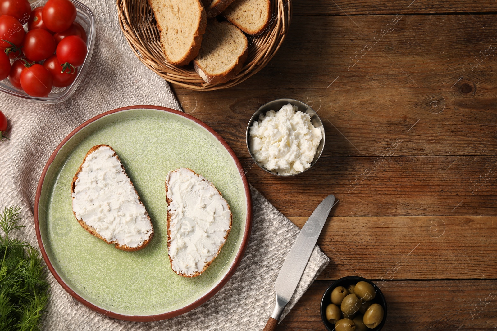 Photo of Delicious ricotta bruschettas and products on wooden table, flat lay. Space for text