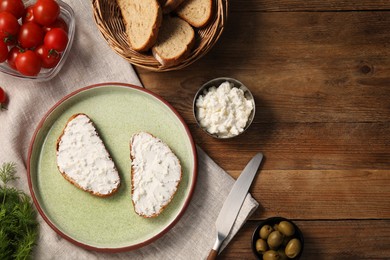 Photo of Delicious ricotta bruschettas and products on wooden table, flat lay. Space for text