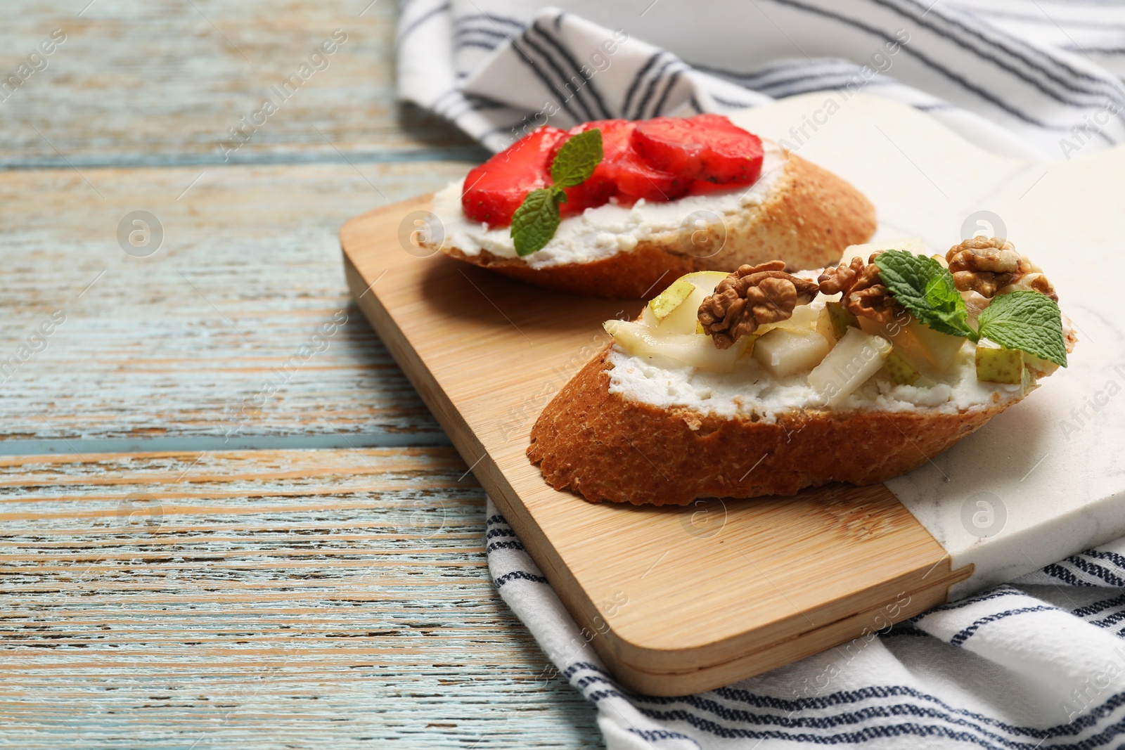 Photo of Delicious ricotta bruschettas with pear, strawberry and walnut on wooden table, closeup. Space for text