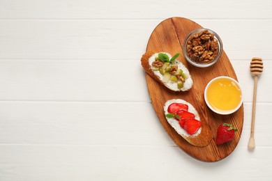 Delicious ricotta bruschettas with pear, strawberry and walnut on white wooden table, top view. Space for text