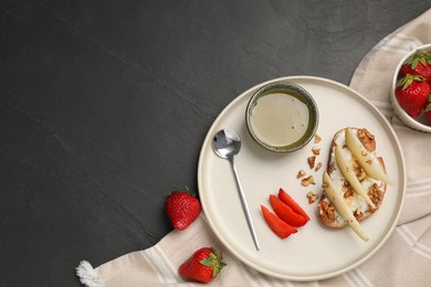 Photo of Delicious ricotta bruschetta with pear, strawberry and walnut on black table, flat lay. Space for text