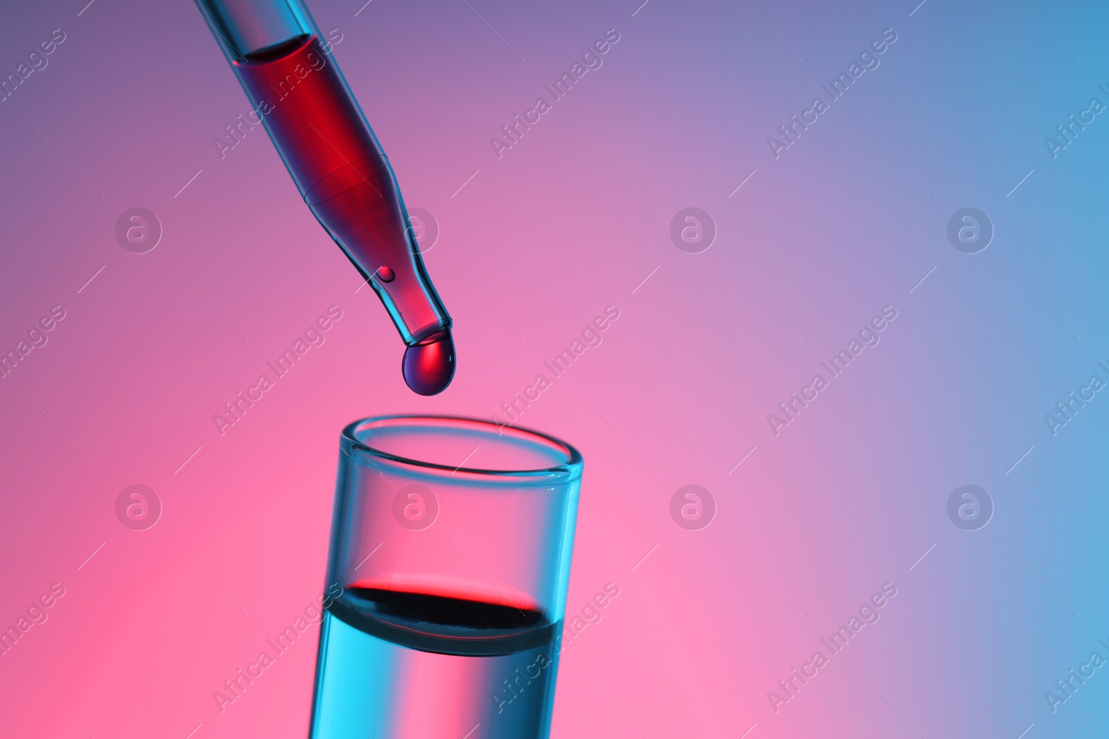 Photo of Dripping liquid from pipette into test tube on color background, closeup. Space for text