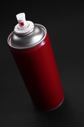 Photo of Red spray paint can on dark gray background, closeup