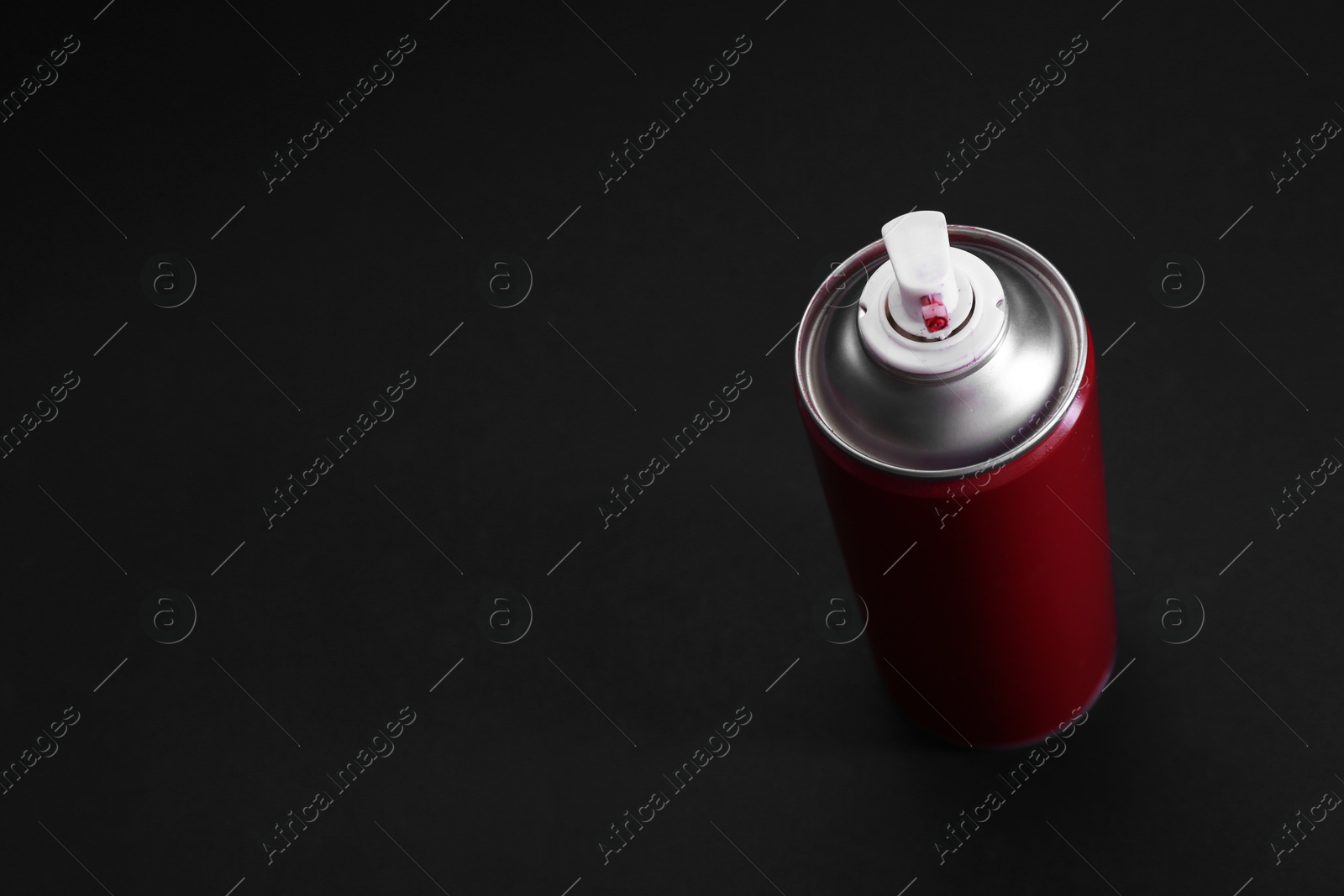 Photo of Red spray paint can on dark gray background, above view. Space for text