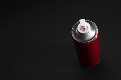 Red spray paint can on dark gray background, above view. Space for text