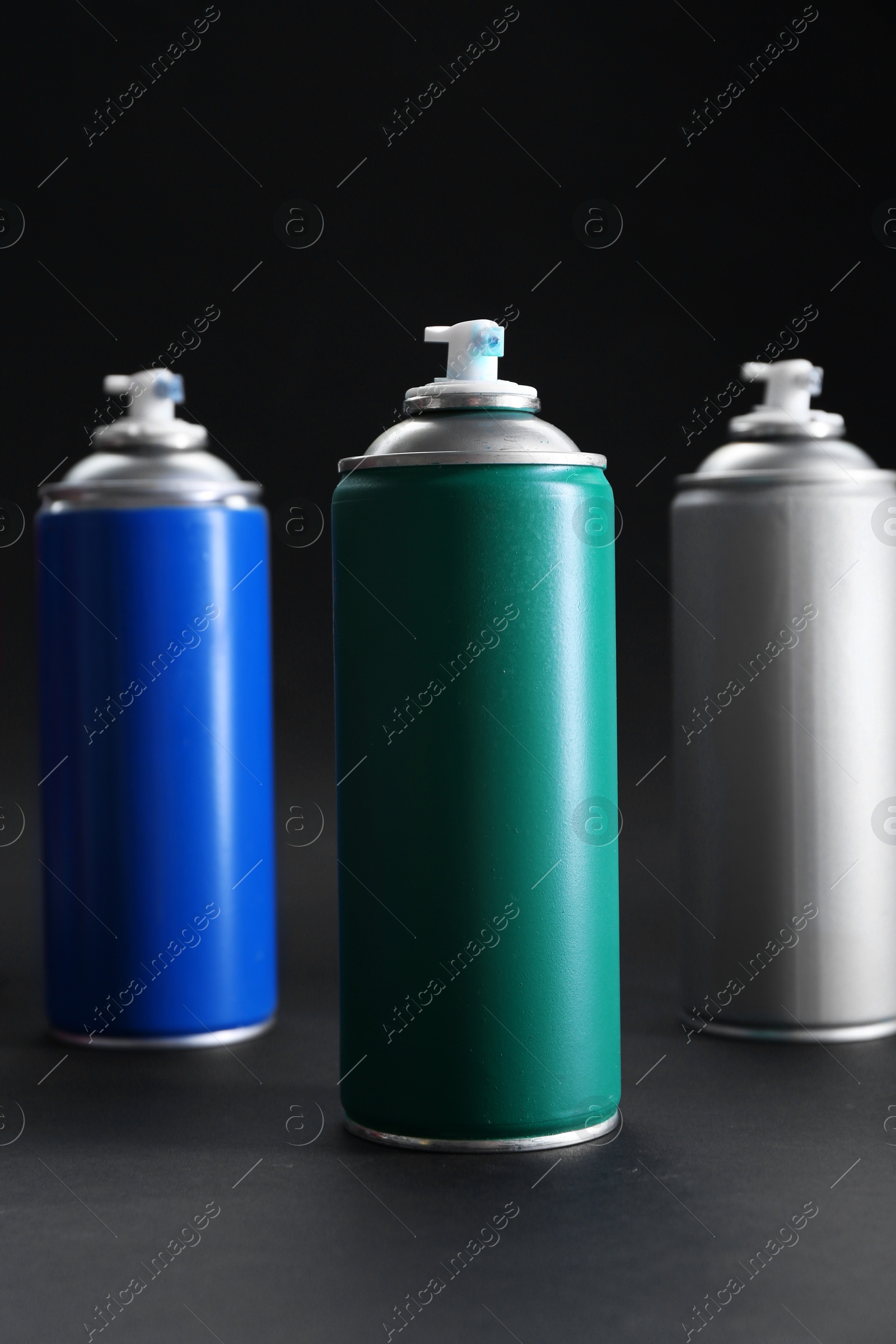 Photo of Many spray paint cans on dark gray background