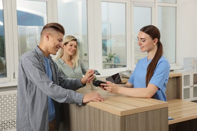 Photo of Receptionist taking payment from client via terminal at hospital