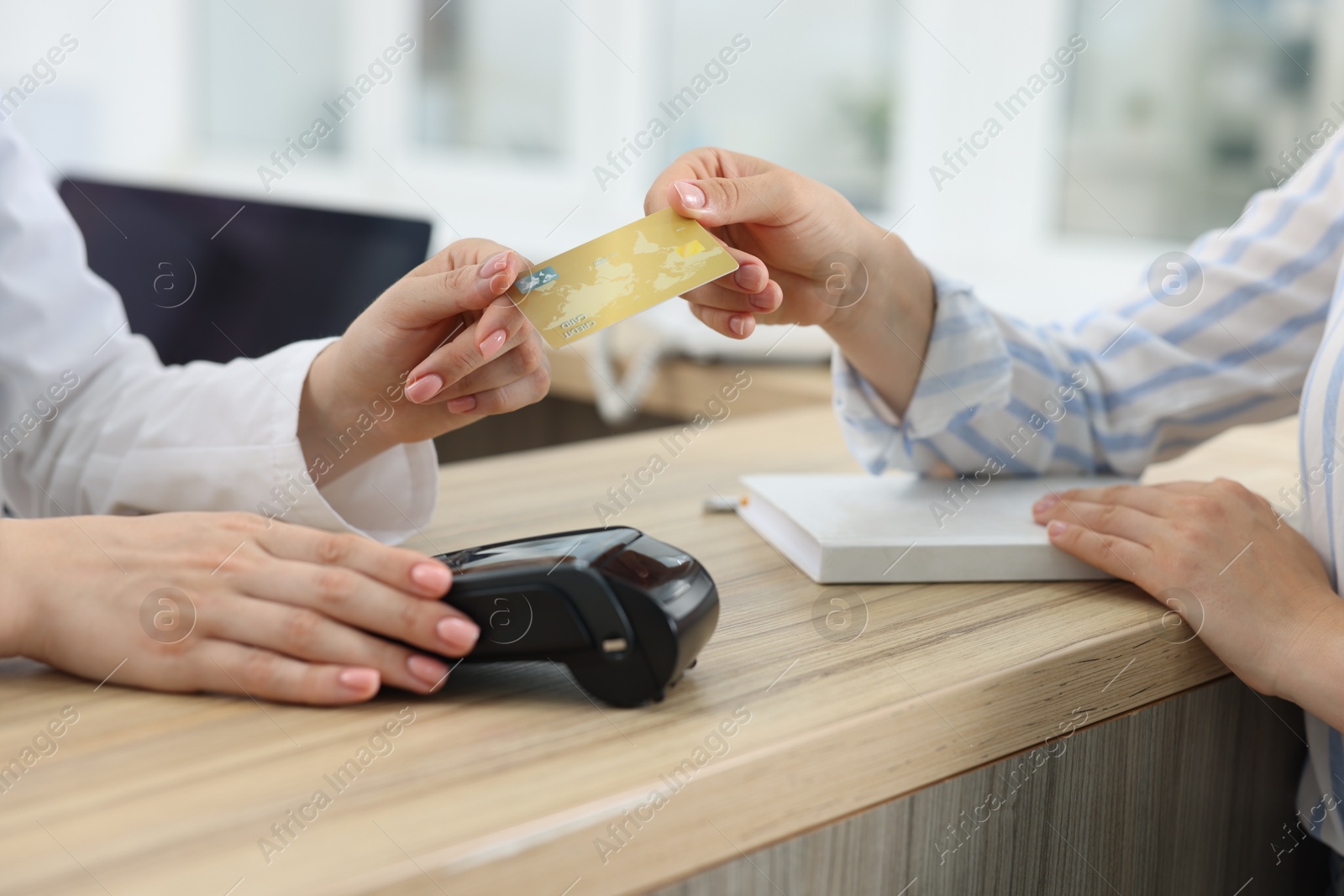 Photo of Receptionist taking credit card from client at hospital, closeup