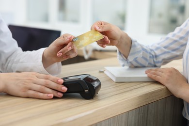 Receptionist taking credit card from client at hospital, closeup