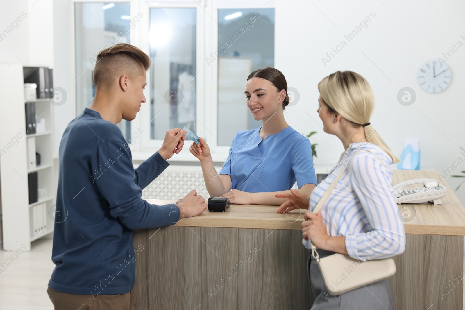 Photo of Receptionist taking payment from client via terminal at hospital