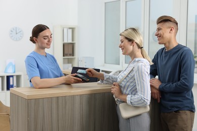 Photo of Receptionist taking payment from client via terminal at hospital
