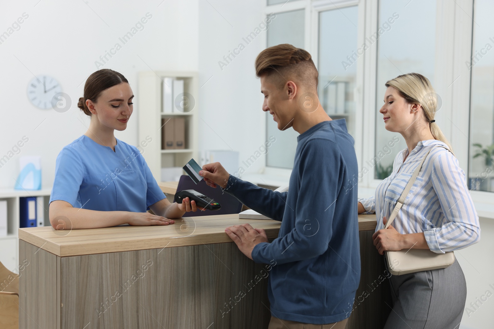 Photo of Receptionist taking payment from client via terminal at hospital