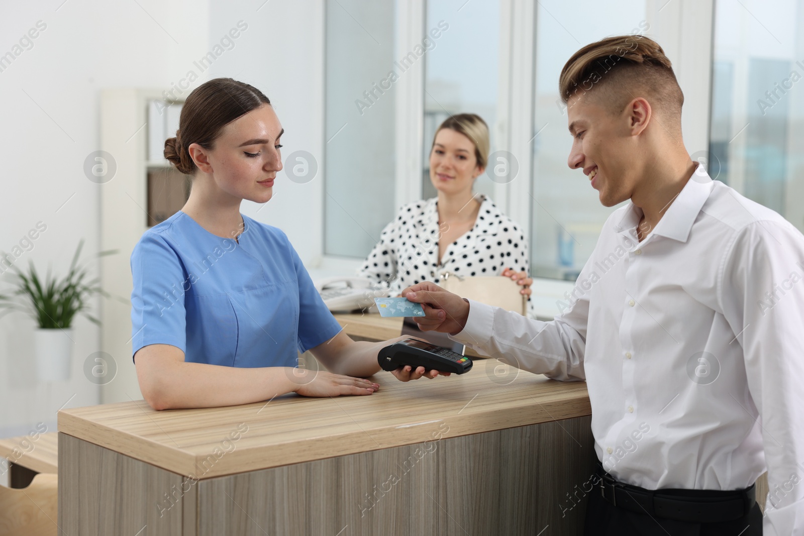 Photo of Receptionist taking payment from client via terminal at hospital