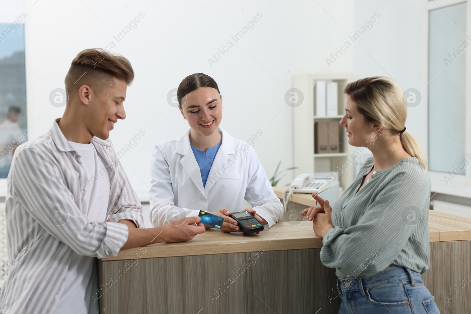 Photo of Receptionist taking payment from client via terminal at hospital