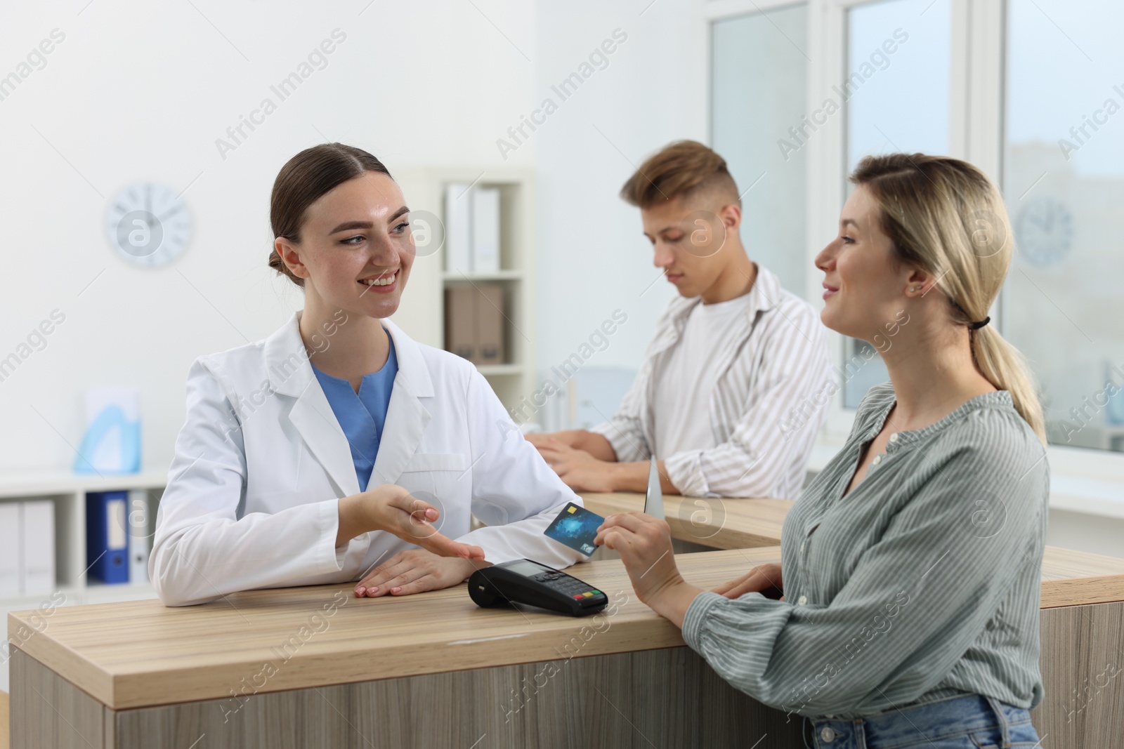 Photo of Receptionist taking payment from client via terminal at hospital