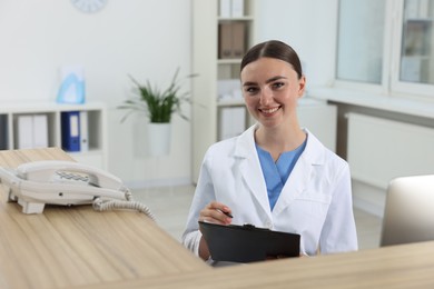 Photo of Professional receptionist working at wooden desk in hospital